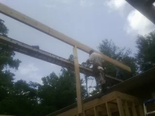 Carpenter setting a ridge beam over a new addition frame — Ice Dam Removal by Roofing Brothers in Waverly