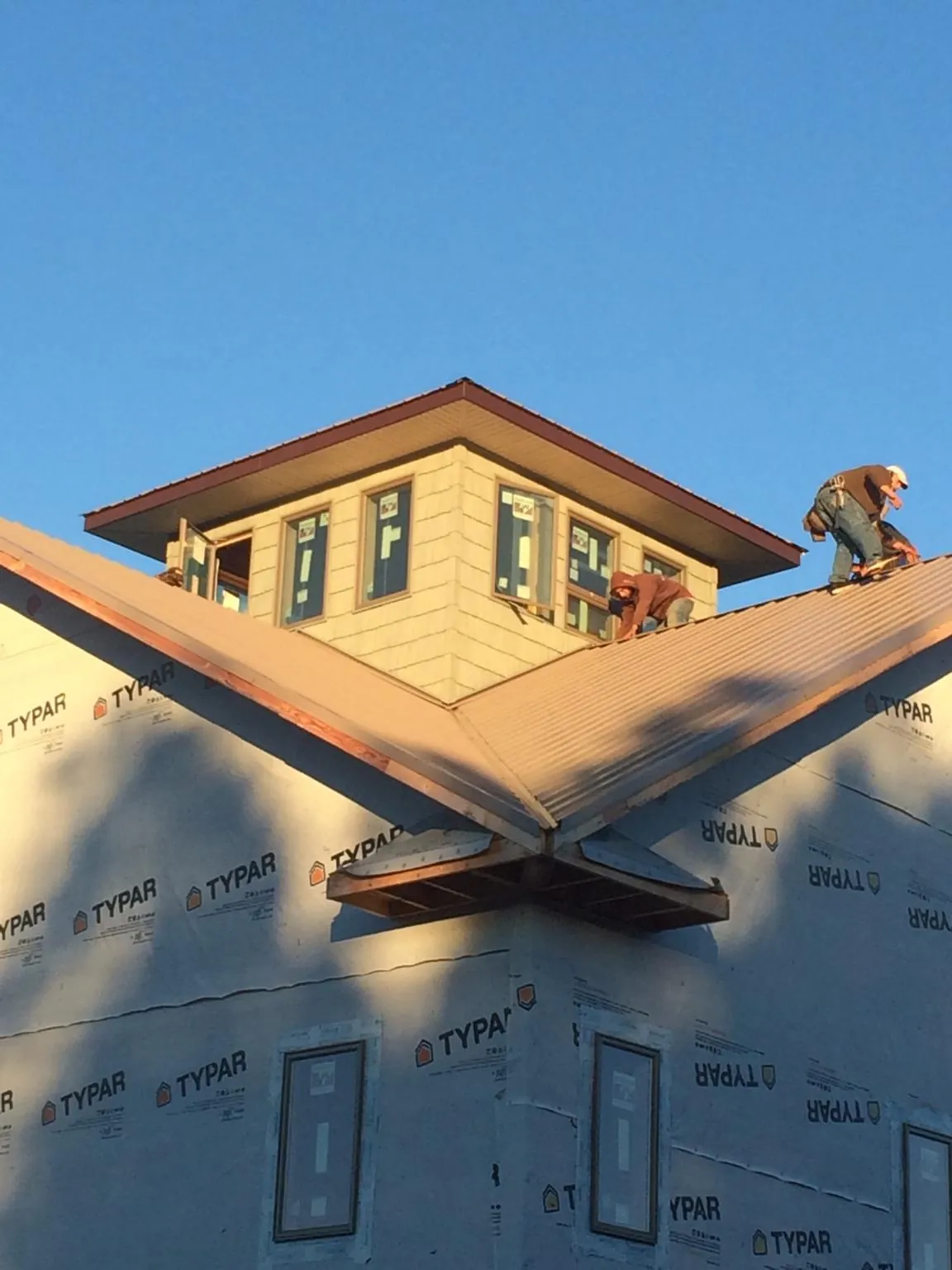 Roofers working around a rooftop cupola on a new metal roof at sunset — Roof Waterproofing in Waverly by Roofing Brothers